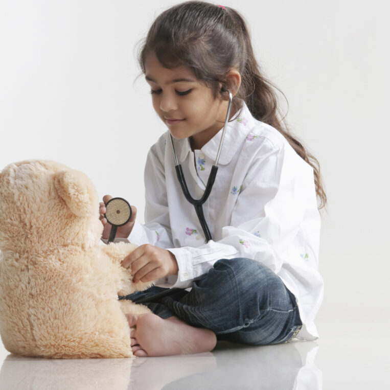 Girl playing doctor with teddy bear