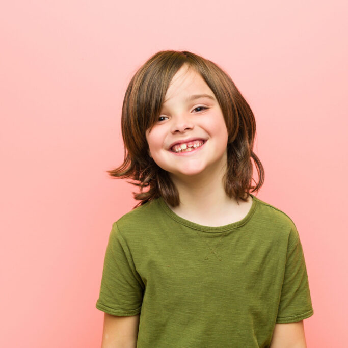 Little caucasian boy playing against a pink background Little caucasian boy playing against a pink background