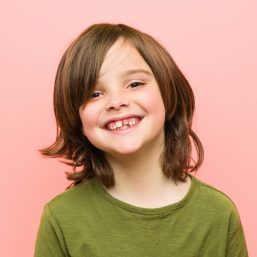 Little caucasian boy playing against a pink background kid smiling after visit with pediatric care