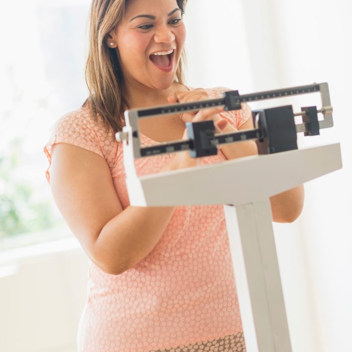 Happy woman standing on scale women's weight loss